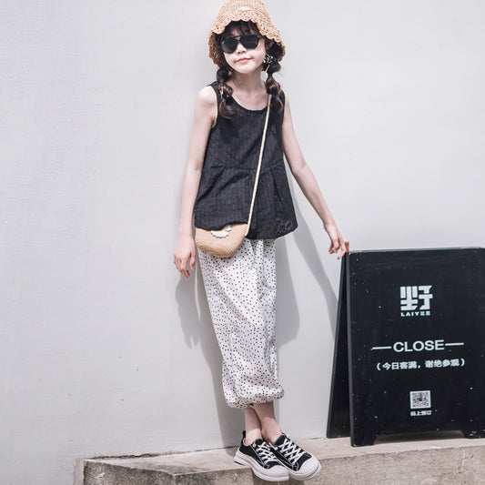 Child wearing a black tank, straw hat, and patterned pants