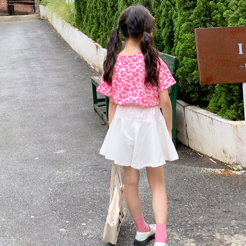 child in a pink leopard print top and white skirt