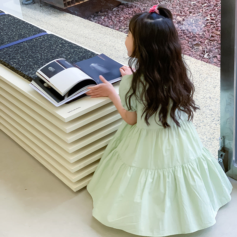 Child in a mint green dress looking at a book