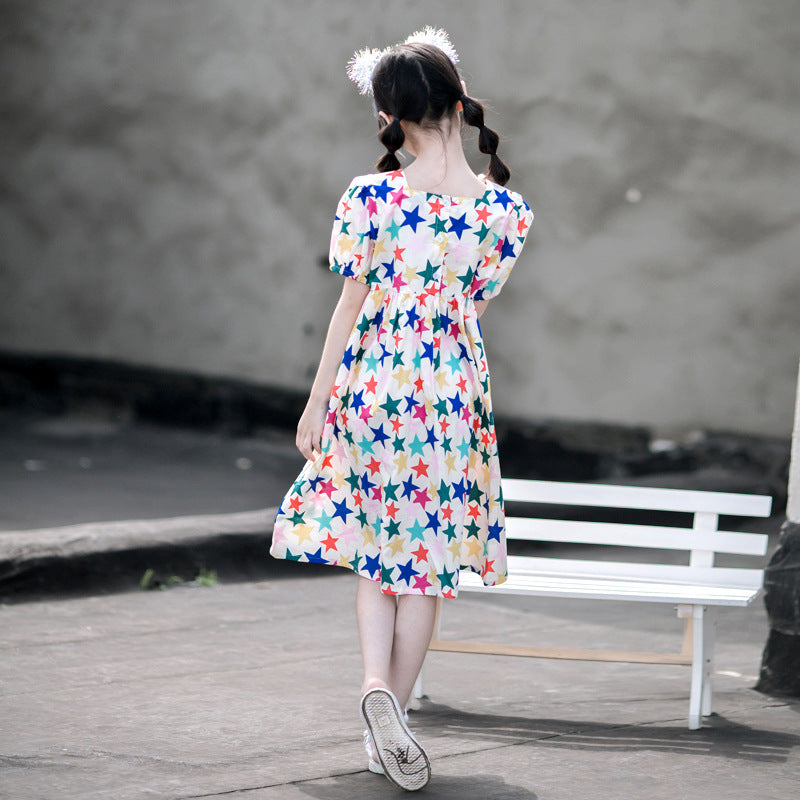 child in a star-printed dress and sneakers