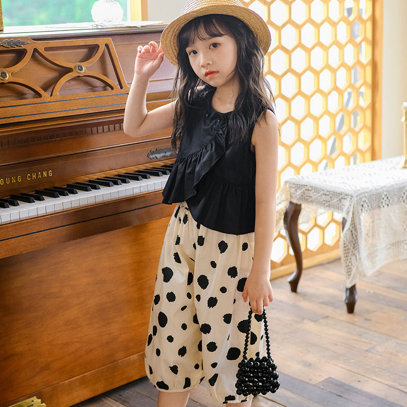 kid girl in a black top and polka-dot skirt